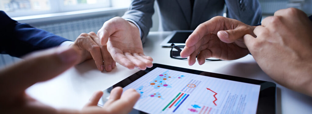 Three business people examining graphs on the screen of digital tablet