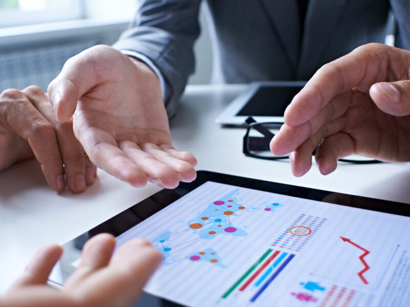 Three business people examining graphs on the screen of digital tablet