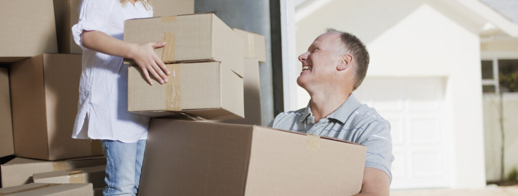 Father and daughter carrying boxed from moving van