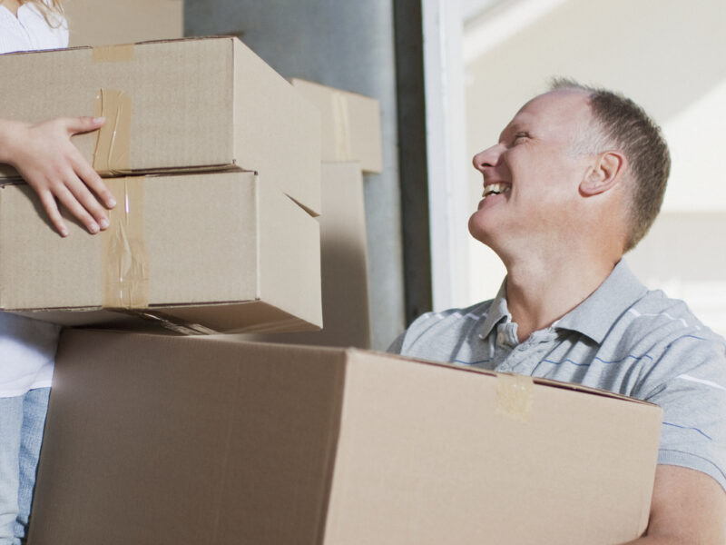 Father and daughter carrying boxed from moving van