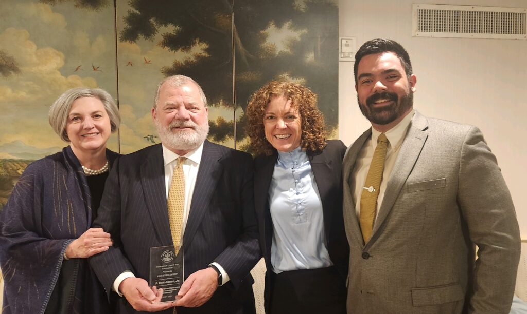 Picture of Attorney Ron Jones Receiving Pro Bono Award - Pictured left to right: Magistrate Judge Mary Gordon Baker, Smith Debnam Partner (and honoree), J. Ronald Jones, Jr., Magistrate Judge Molly Cherry, and Smith Debnam Associate Attorney Lucas Fautua.
